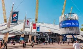 Exterior of a stadium with a large sign reading 'welcome back,' featuring people walking outside.