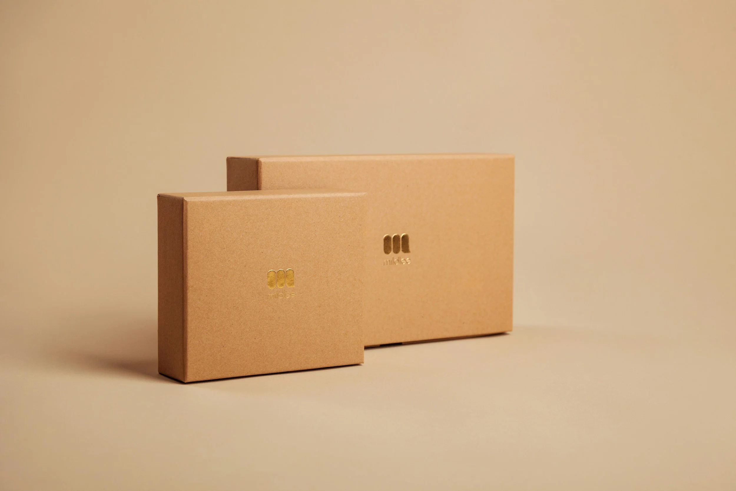Two beige boxes with gold embossed logo on a plain beige background.