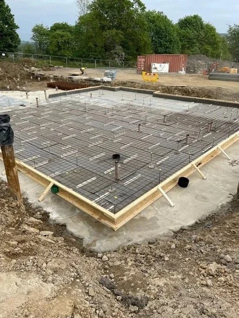 Construction site with a concrete foundation and steel reinforcement for a building floor, with pipes protruding from the ground