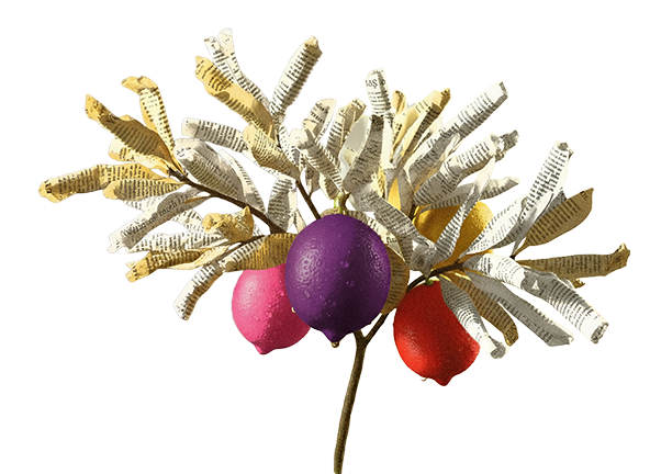 Decoração de festa com frutas artificiais feitas de jornal colorido, incluindo uma uva roxa, uma uva rosa e uma uva vermelha