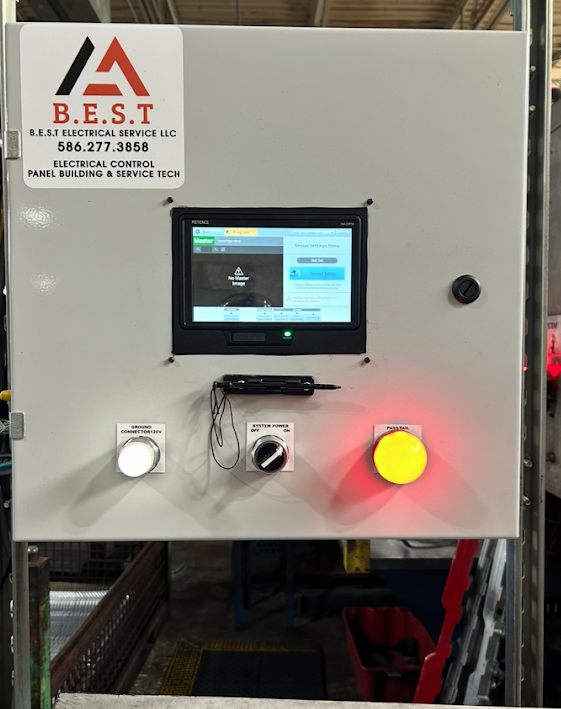 Electrical control panel with a touchscreen display, a white ground connection knob, a black system power knob, and a large yellow emergency stop button, with the company logo and contact information on top.