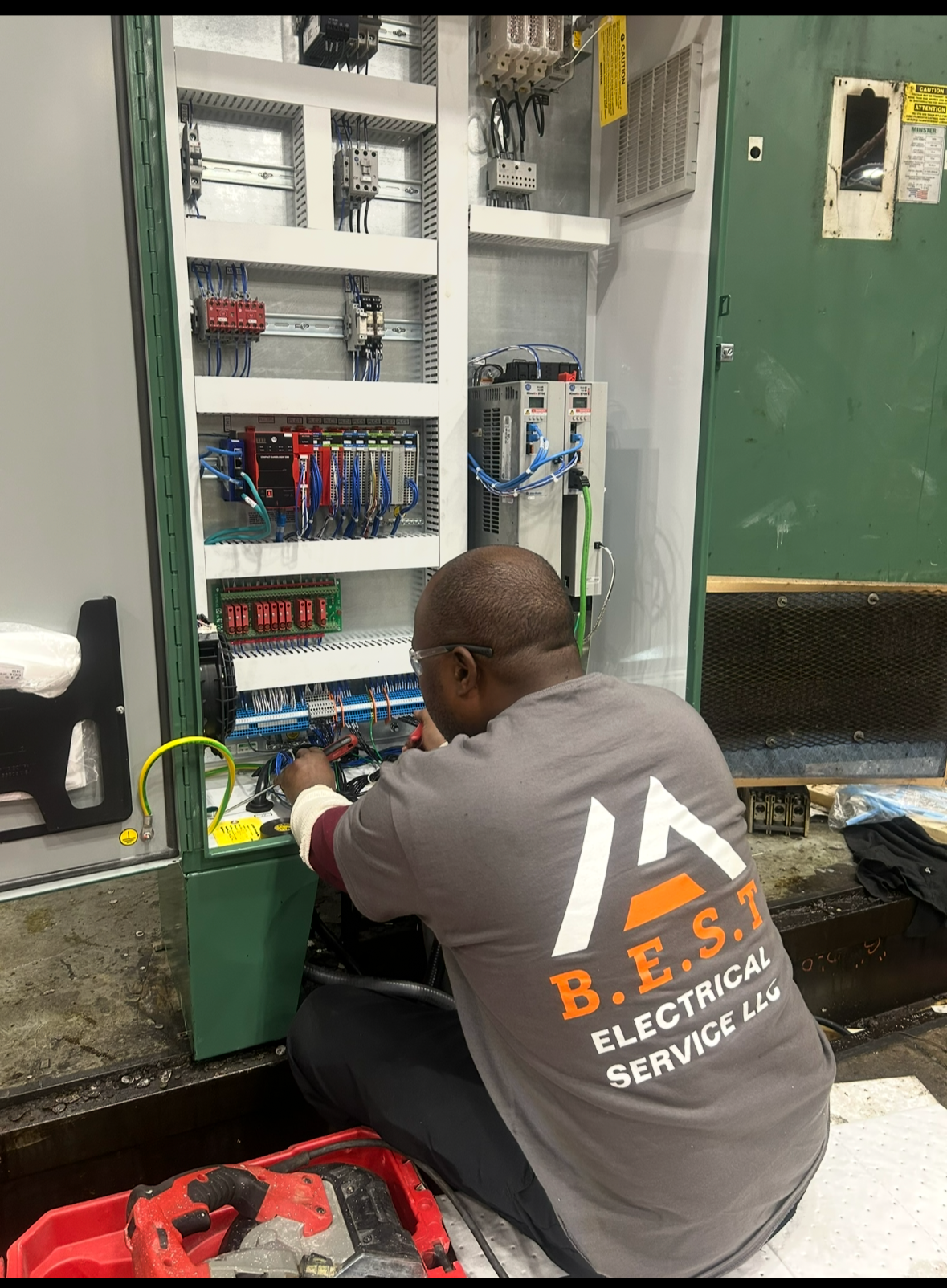 A technician working on an electrical control panel in an industrial setting.