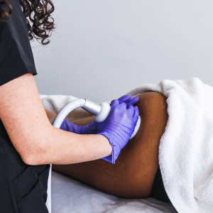 A healthcare professional wearing purple gloves performing an ultrasound on a patient's abdomen.