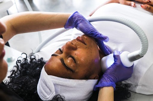 A woman receiving a facial treatment with a suction device, lying down with eye protection on.