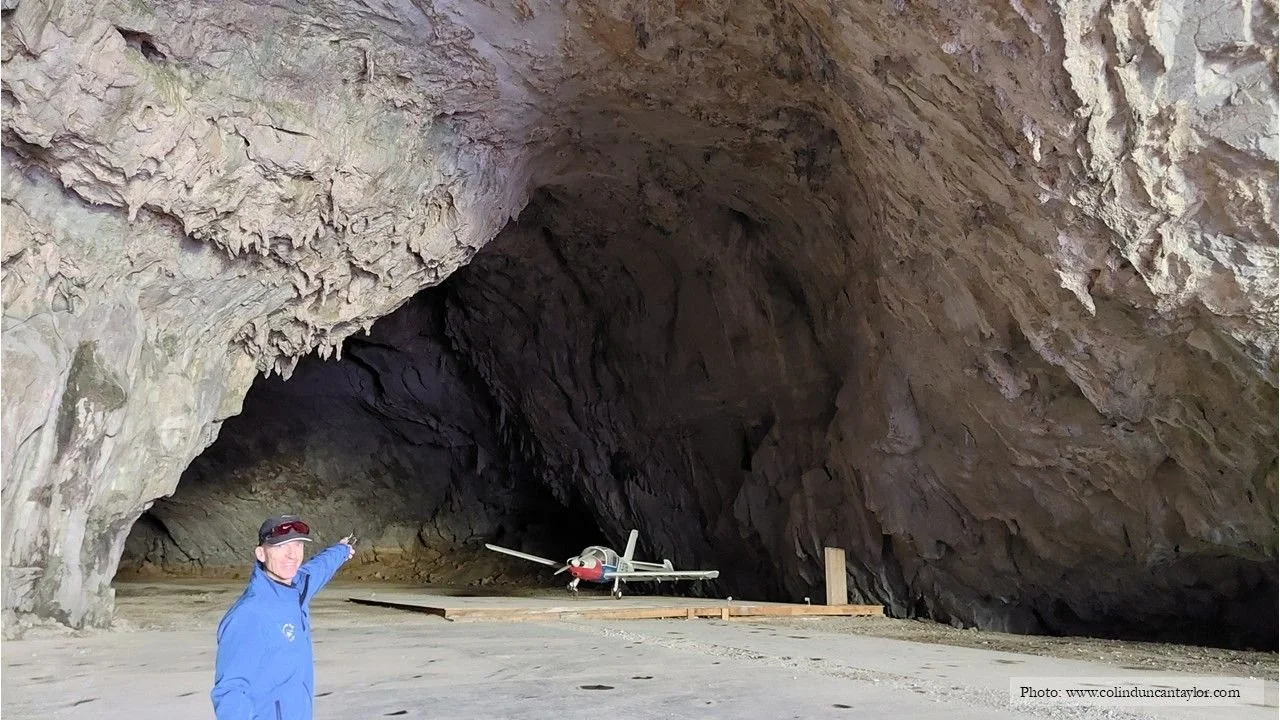 At the Grotte de Bédeilhac in 1972, a test pilot called Georges Bonnet became the first pilot in the world to land in and take off from a cave. Here, the author Colin Duncan Taylor points towards a replica of the plane used by Bonnet.