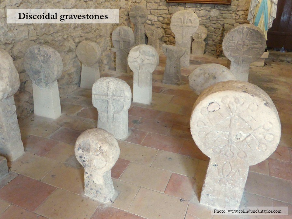A dozen discoidal gravestones inside the porch of the church of Saint Pierre d'Alzonne.