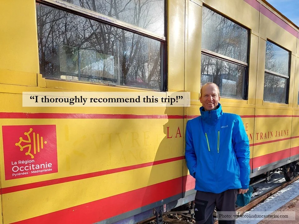 Author Colin Duncan Taylor standing by one of the bright yellow carriages of Le Train Jaune.