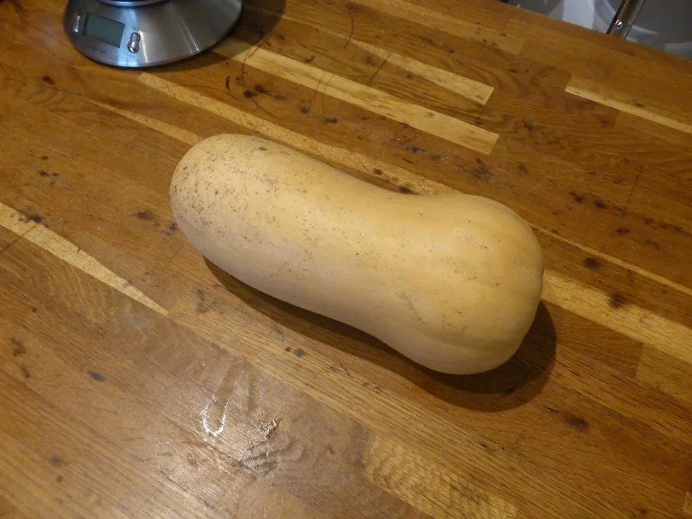 A butternut squash lies on a kitchen worktop.