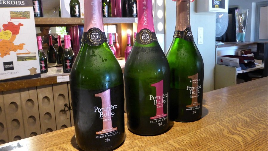 Standing on a bar counter are three bottles of Blanquette de Limoux, the oldest sparkling wine in the world.