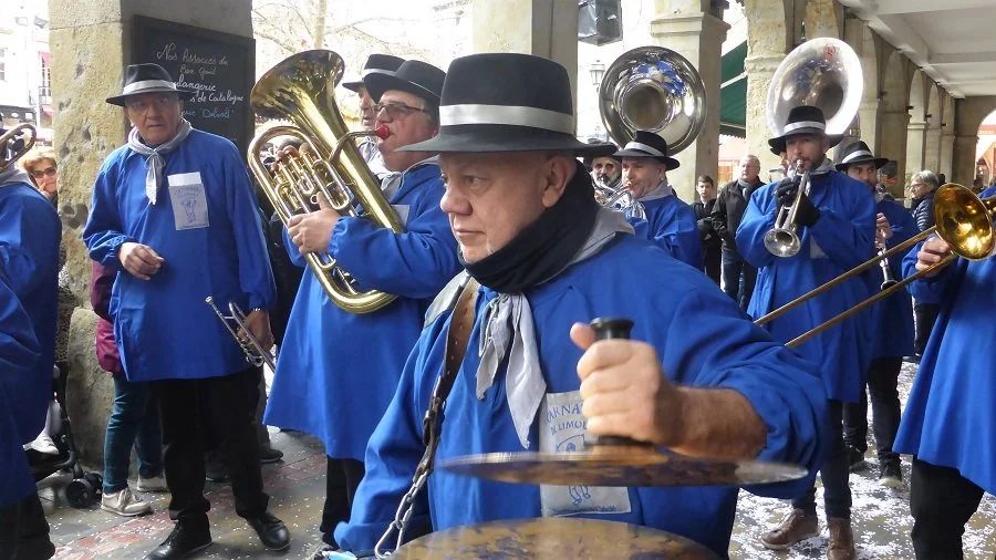 A band of musicians all dressed in blue provide the music for a dance troupe at the Carnival of Limoux.