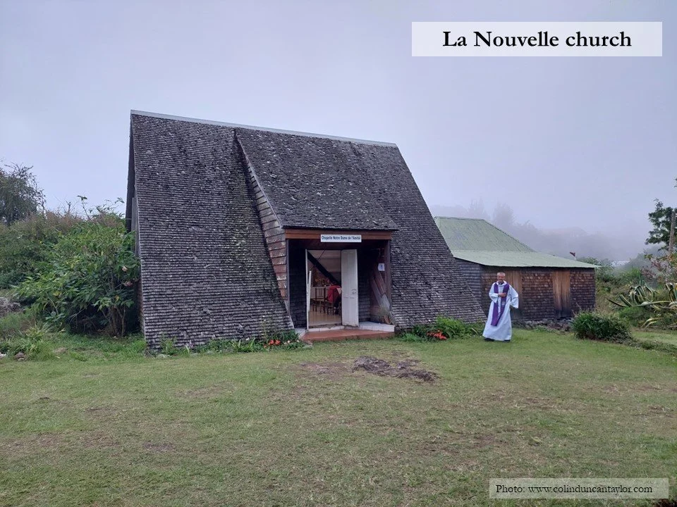 A priest stands outside La Nouvelle church in the mist, waiting to begin a service.