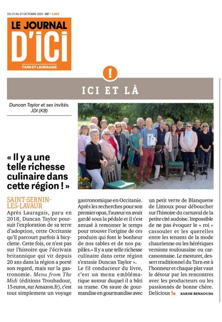 Group of people gathered outdoors, some sitting and some standing, with trees in the background.