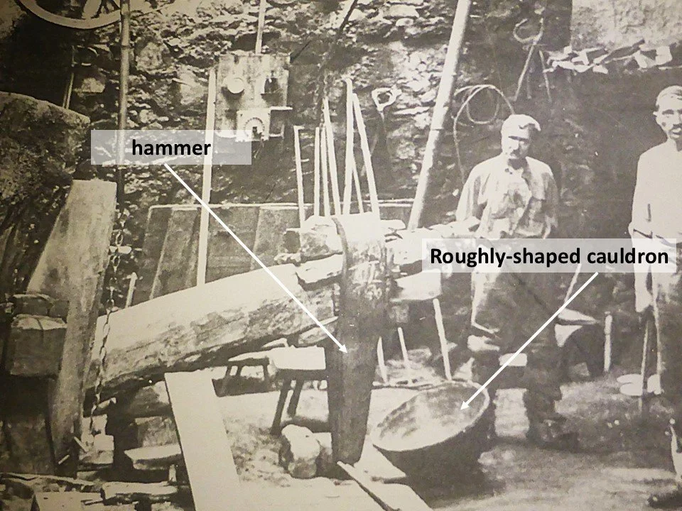 Two cauldron makers working with a hydraulic trip hammer in Durfort.