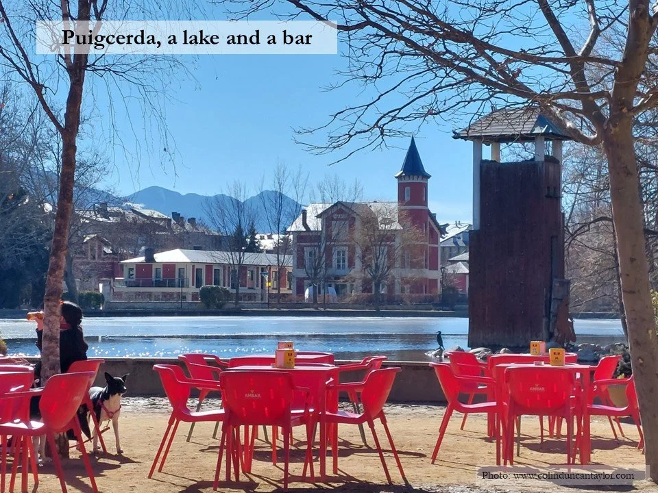 Red tables and sunshine tempt visitors to stop by the lake in the centre of Puigcerda.
