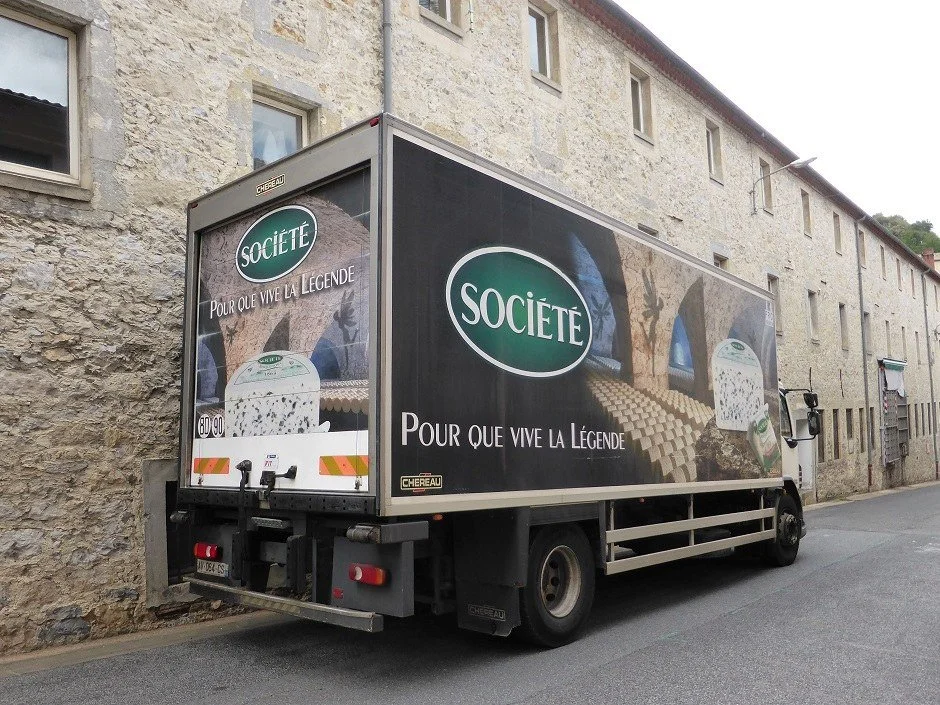 A truck emblazoneed with the name of Société Roquefort and pictures of the company's cheese cellars.