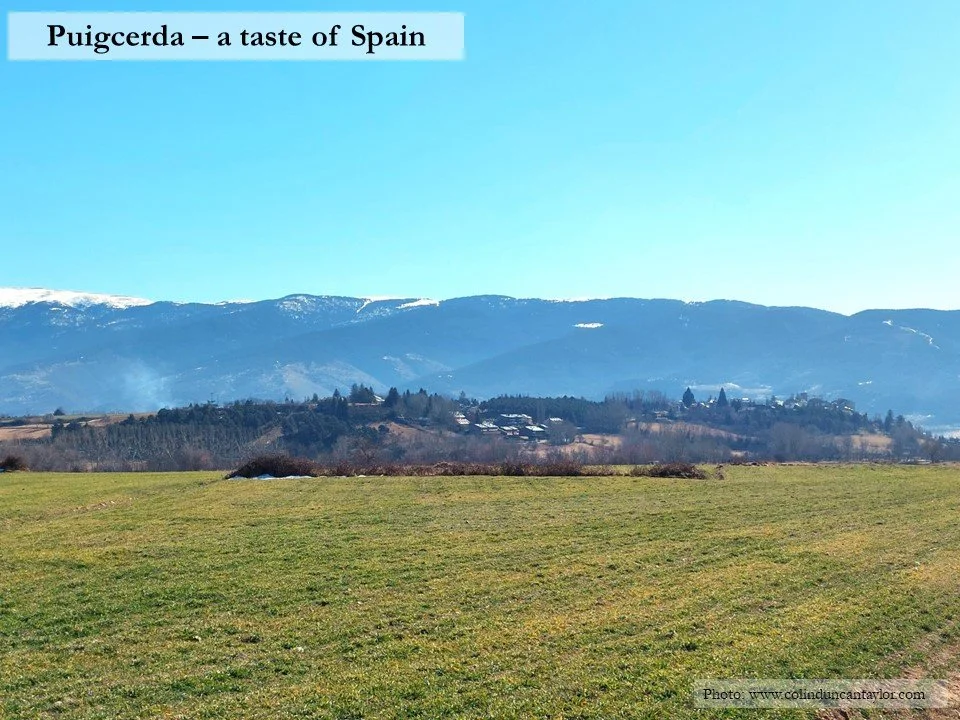 The Spanish town of Puigcerda stands on its mount with Pyrenean peaks in the background.
