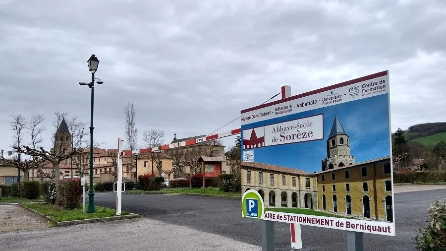 A large sign in a car park in Soreze promotes the historic abbey.