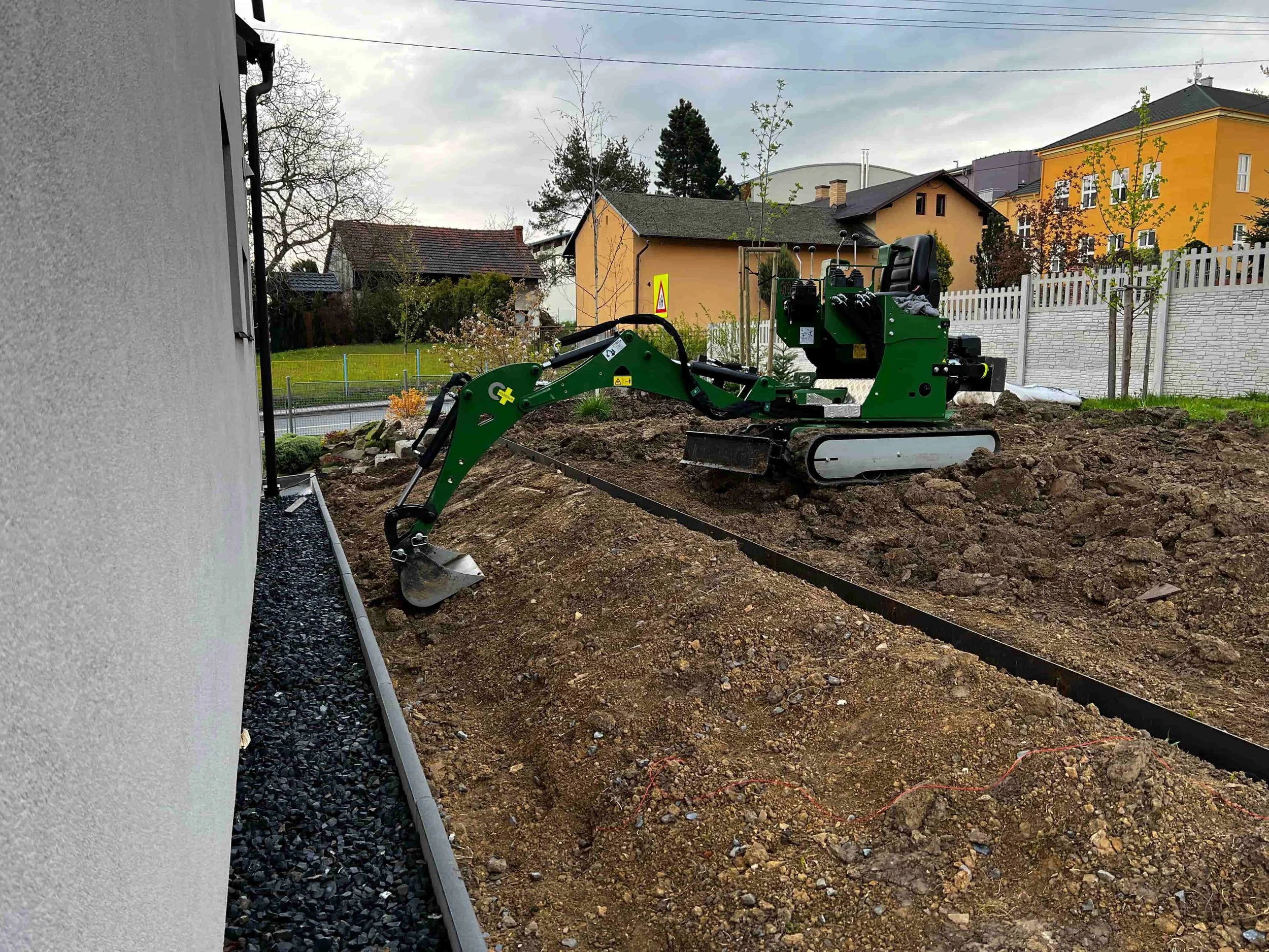 Práce minibagrem při terénních úpravách zahrady u rodinného domu.