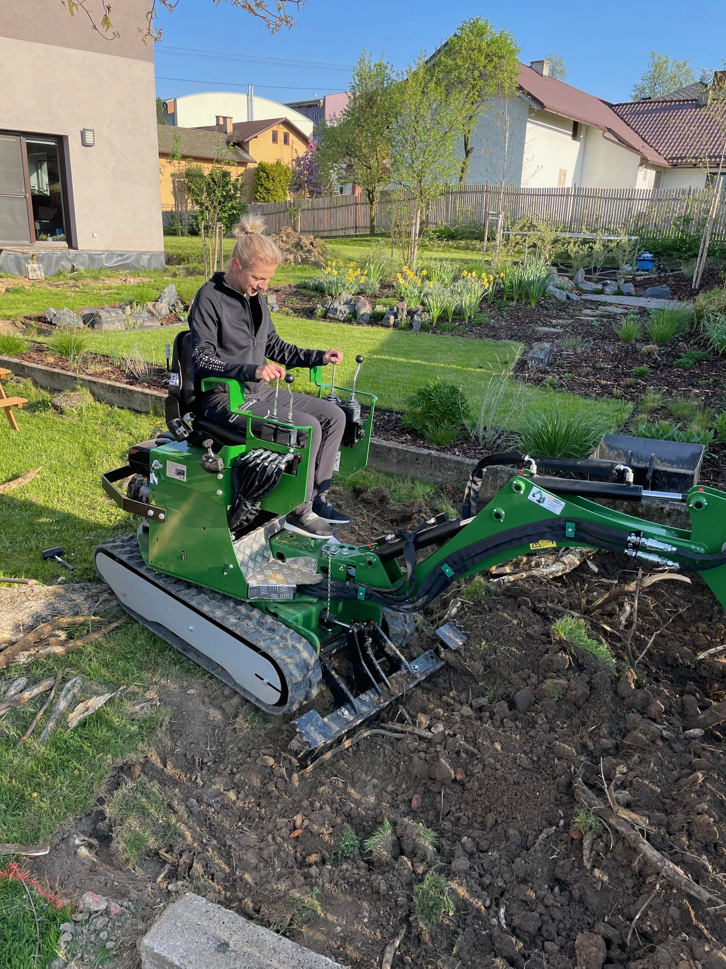 Práce na zahradě při realizaci – obsluha minibagru při terénních úpravách v zahradě.