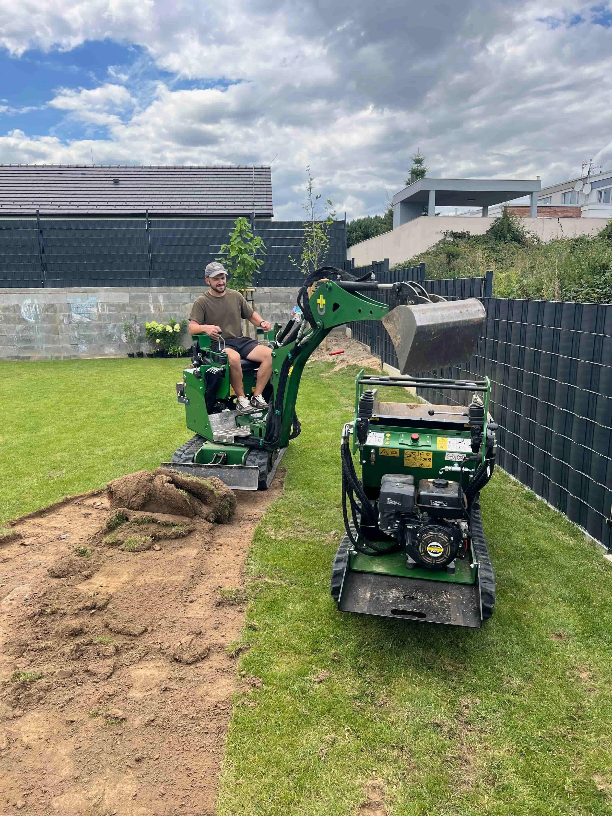 Práce na zahradě při realizaci – obsluha kompaktní stavební techniky na pozemku.