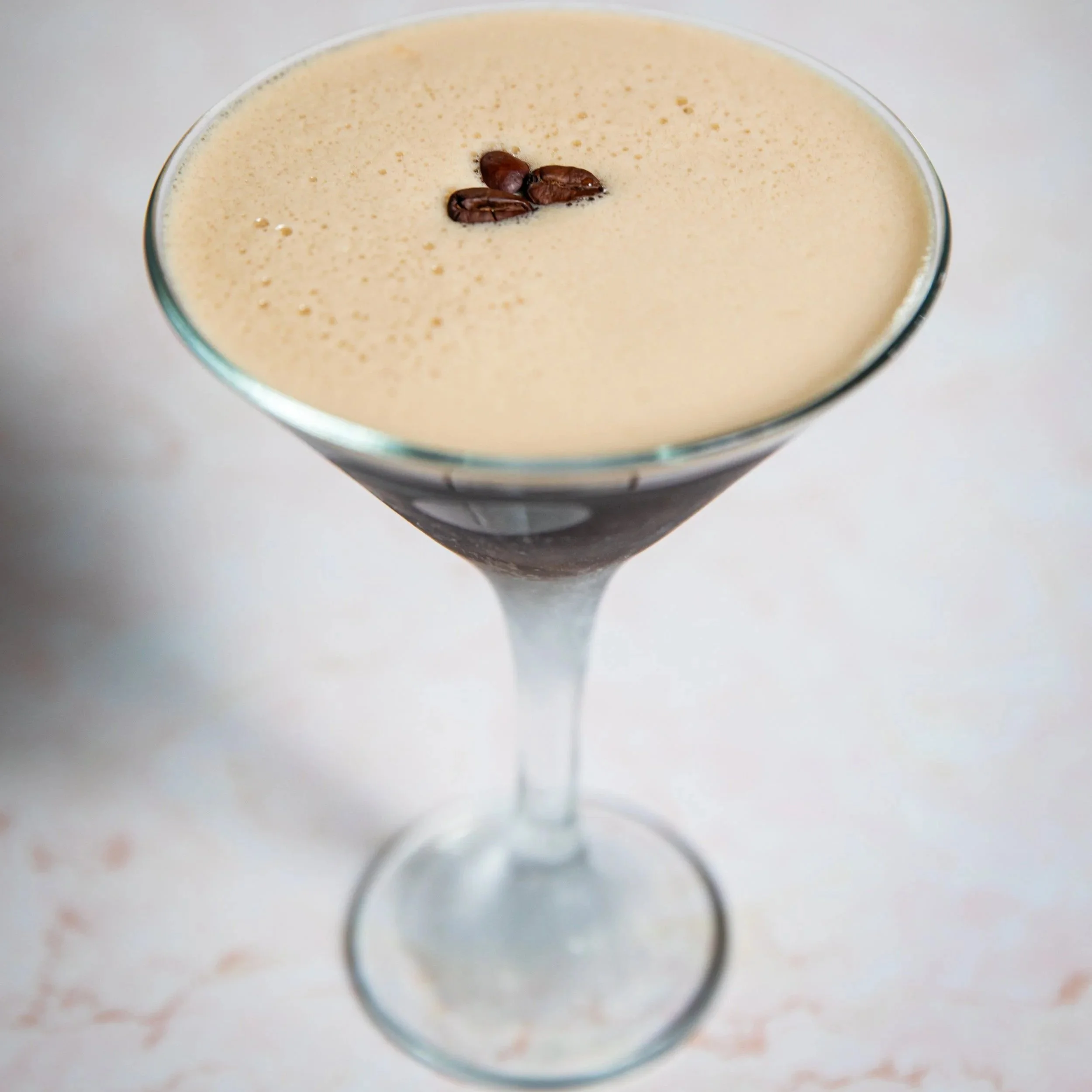 Coffee martini with coffee beans on top in a cocktail glass.