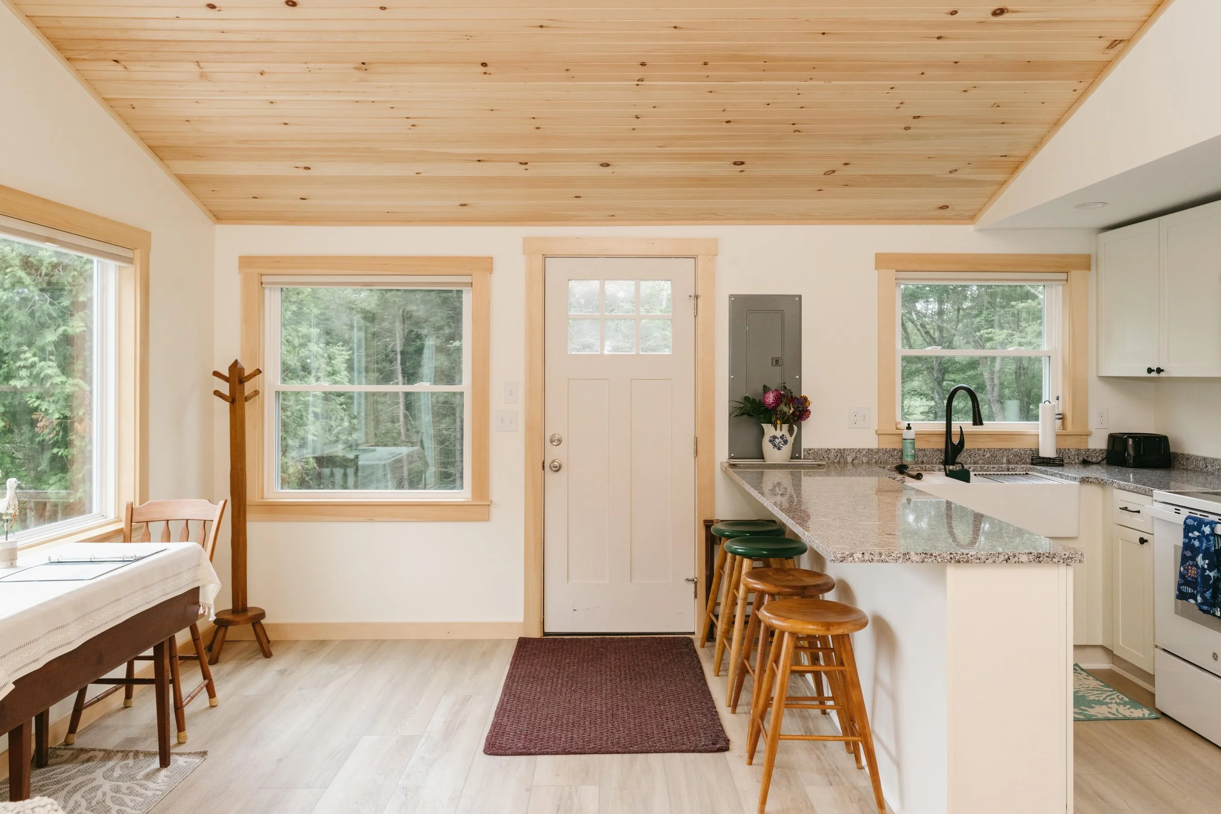 Kitchen with a granite countertop, sink, four bar stools, and a white door with windows leading outside.