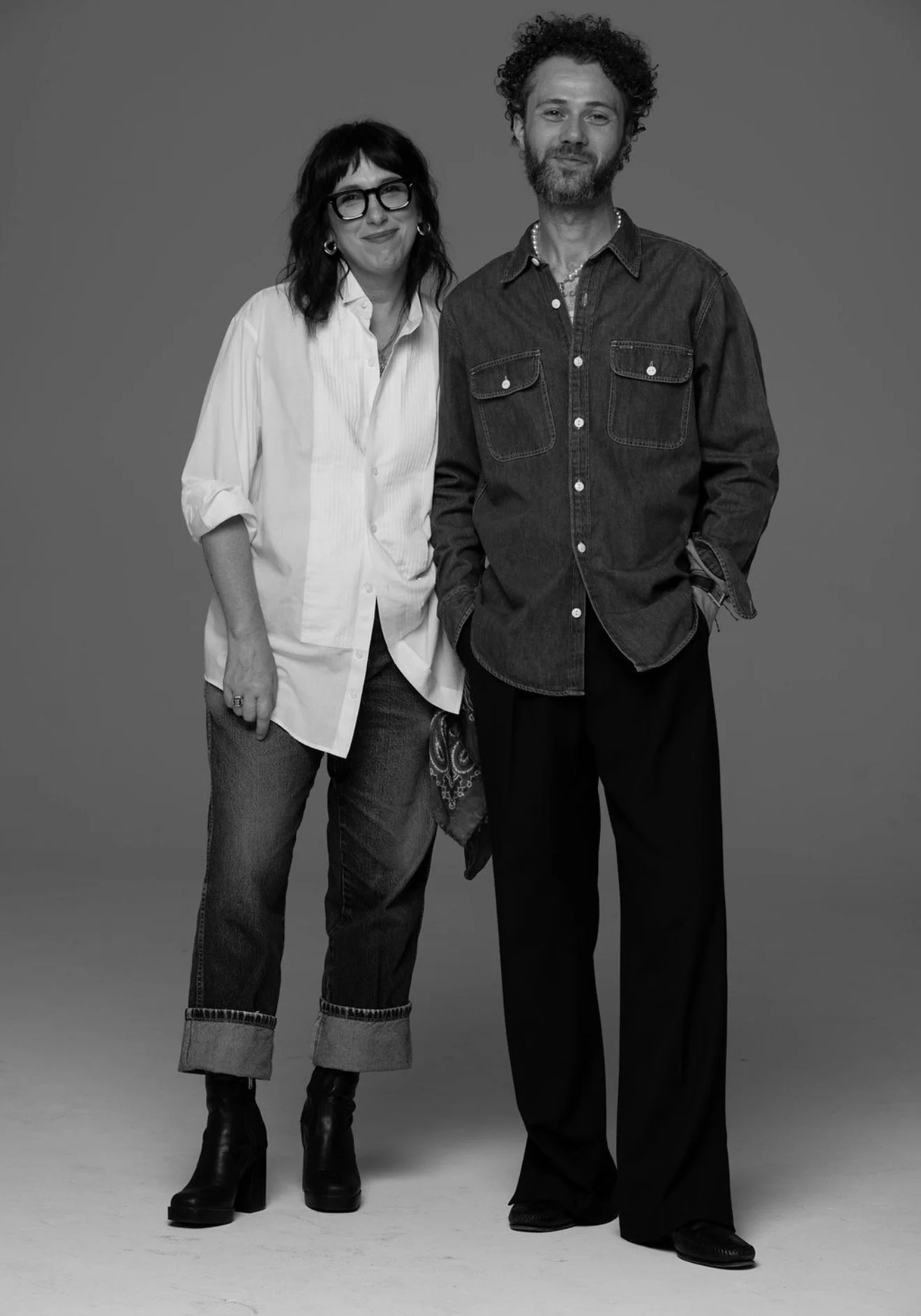 Black-and-white studio portrait of two casually dressed adults posing together.