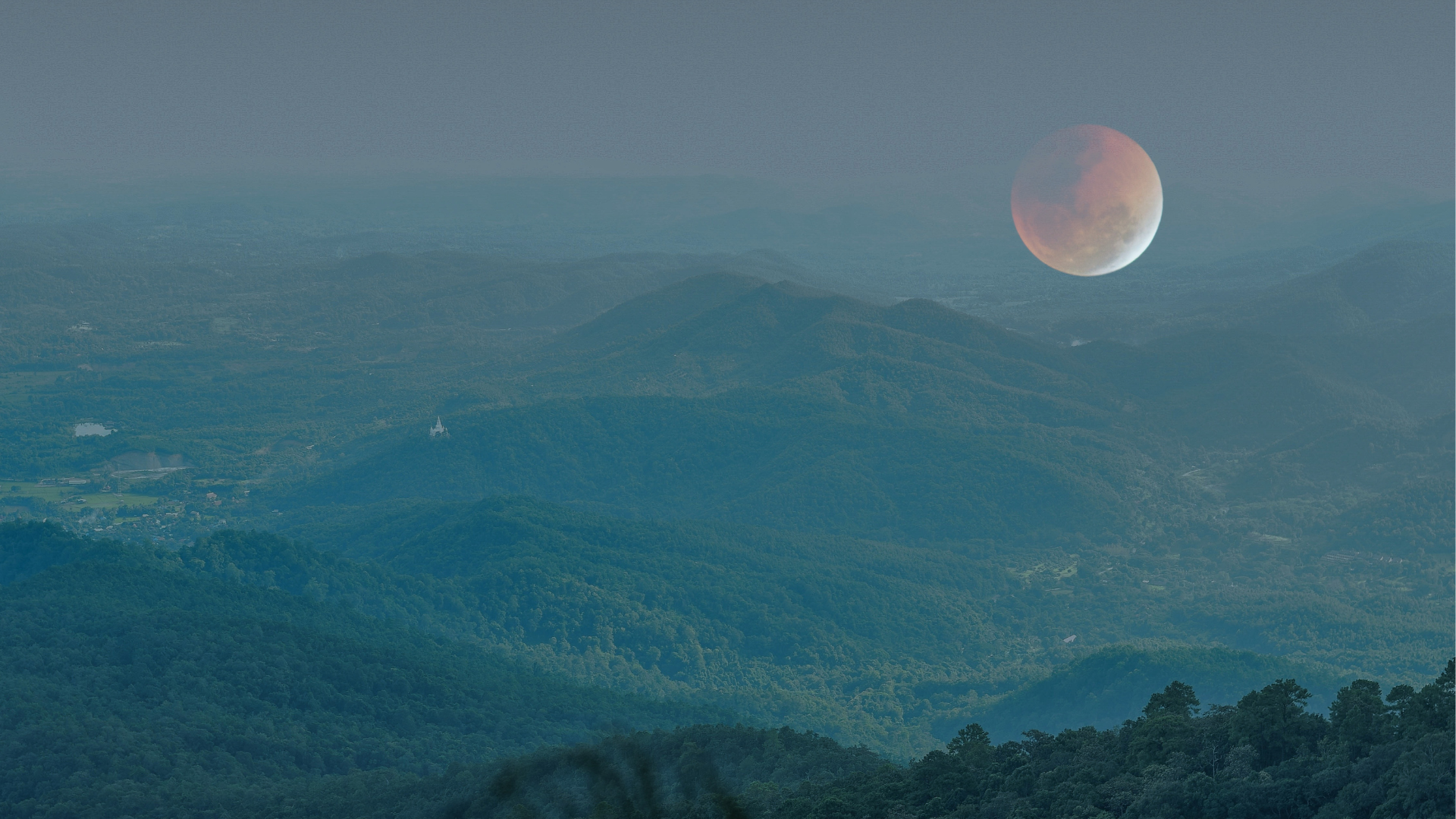 Mountain landscape during twilight with a large, reddish moon in the sky.