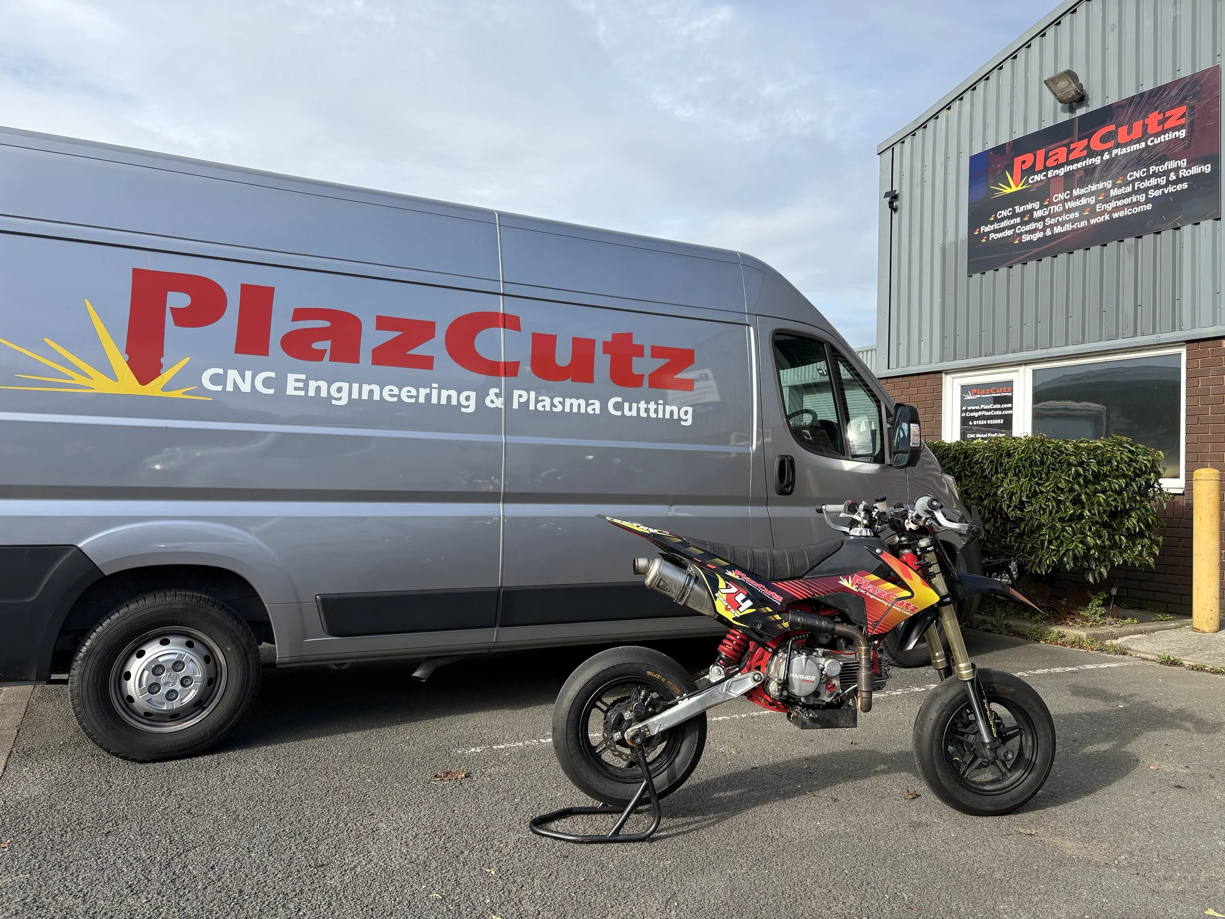 PlazCutz Racing pitbike outside UK CNC engineering workshop with branded race van, showing real race bike development and manufacturing.