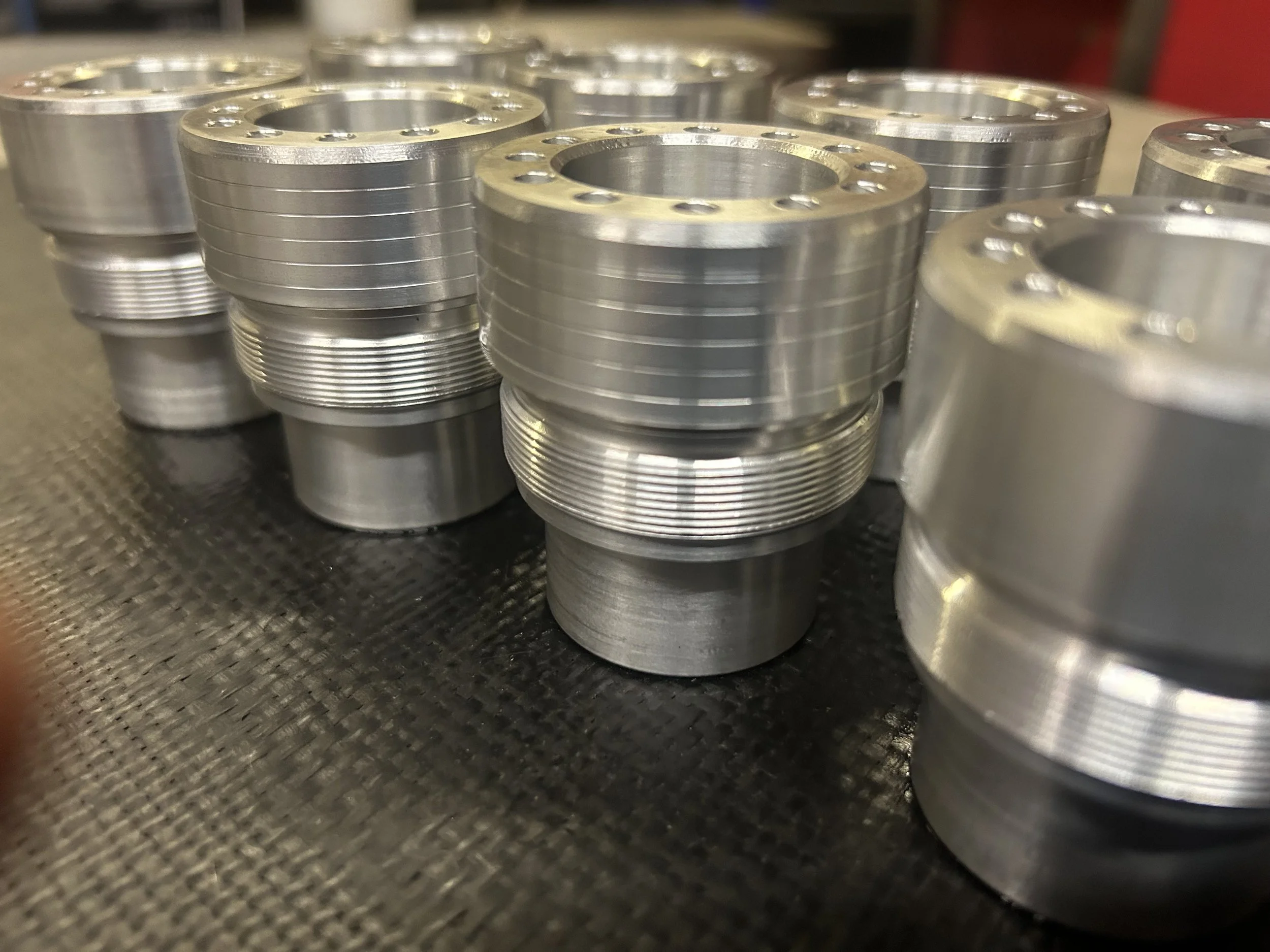 Multiple metal threaded pipe fittings arranged on a textured black surface.