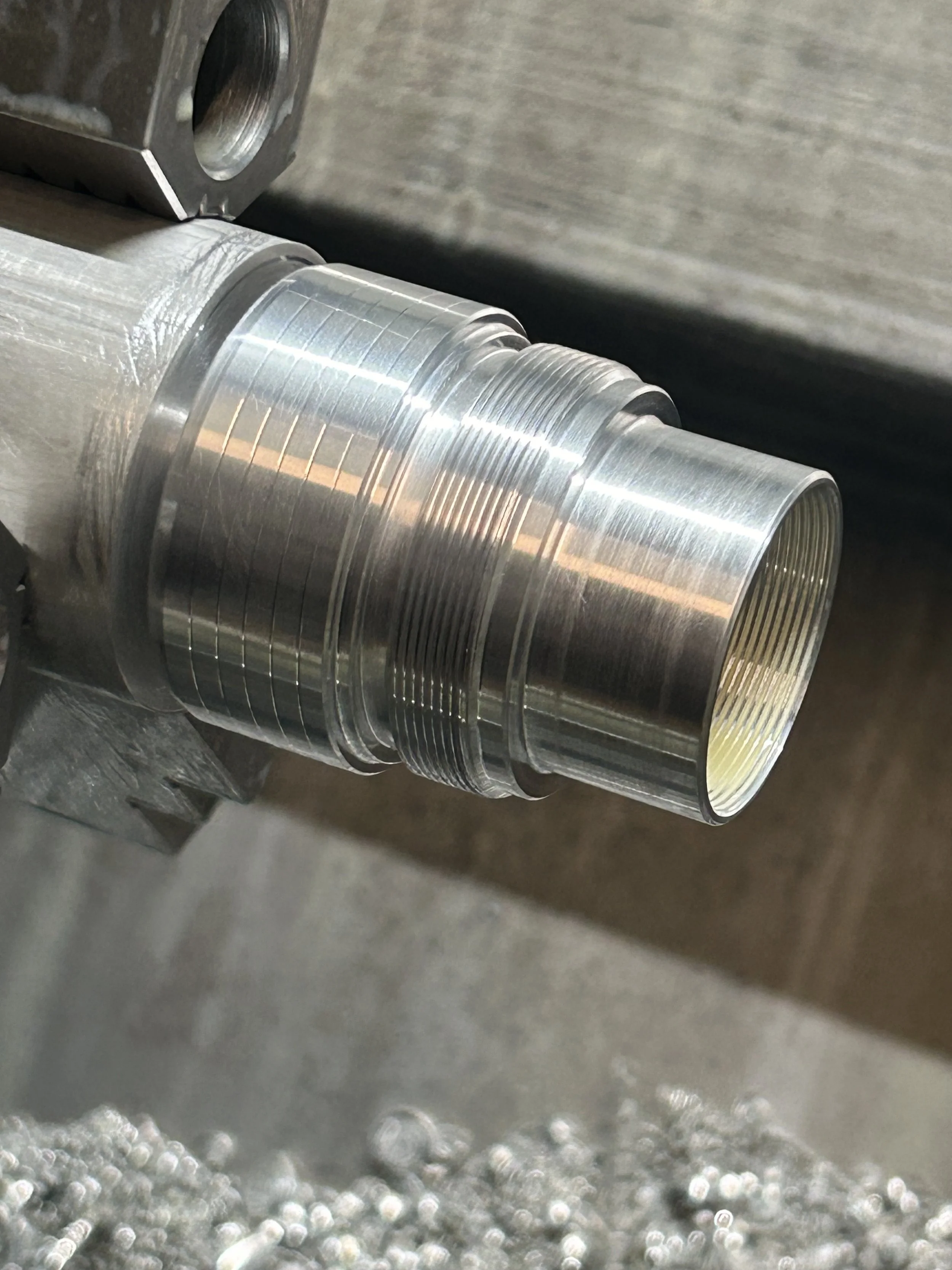 Close-up of a shiny, machined metal cylinder with threaded interior.