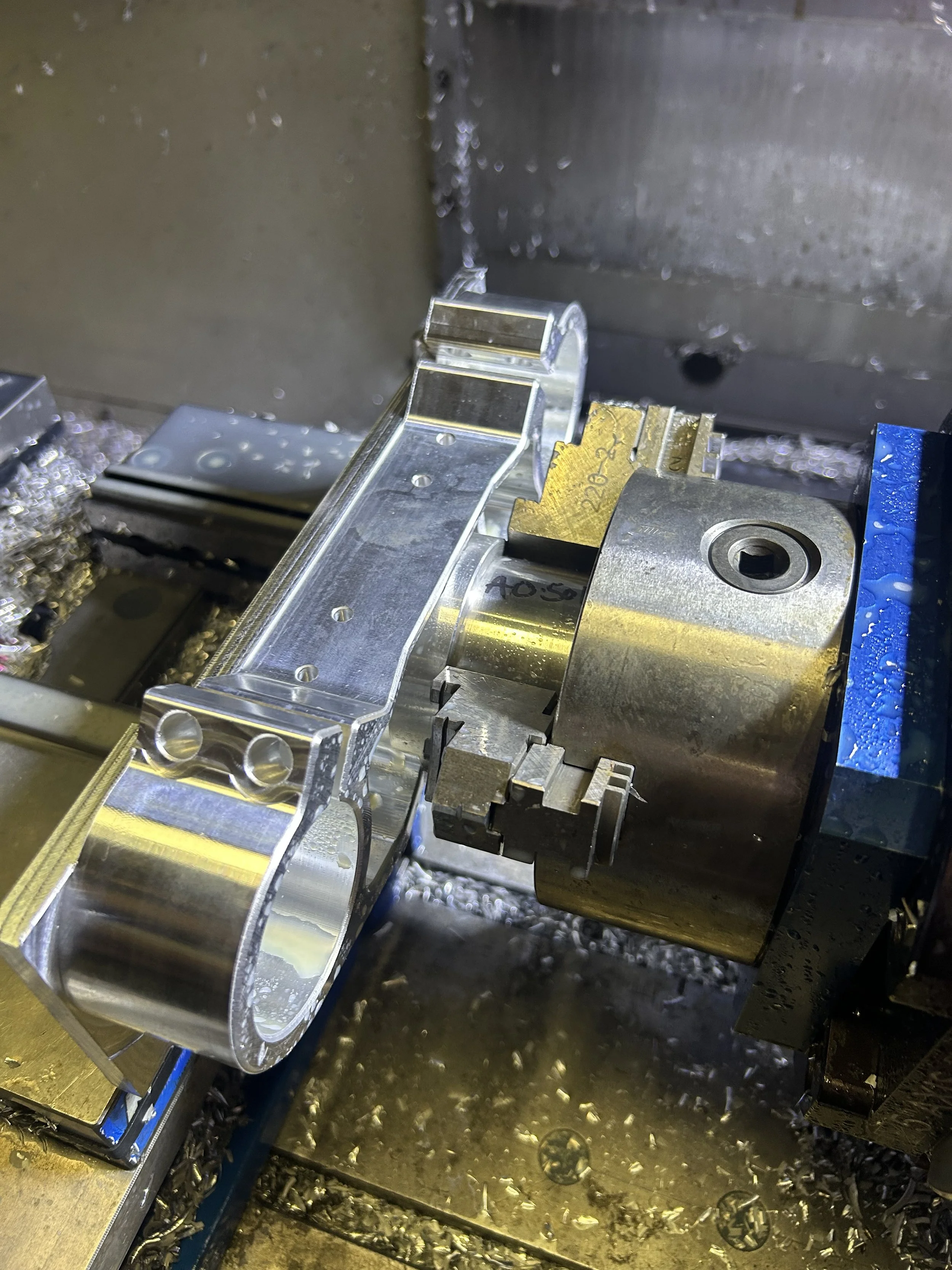 Close-up of a CNC machining process with a metallic part being held and cut by a machine tool.