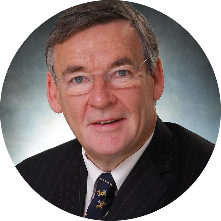 Close-up of our co-inventor, Christopher Chapple, a middle-aged man with gray hair and glasses, wearing a dark pinstripe suit, white shirt, and patterned tie, smiling against a neutral background.