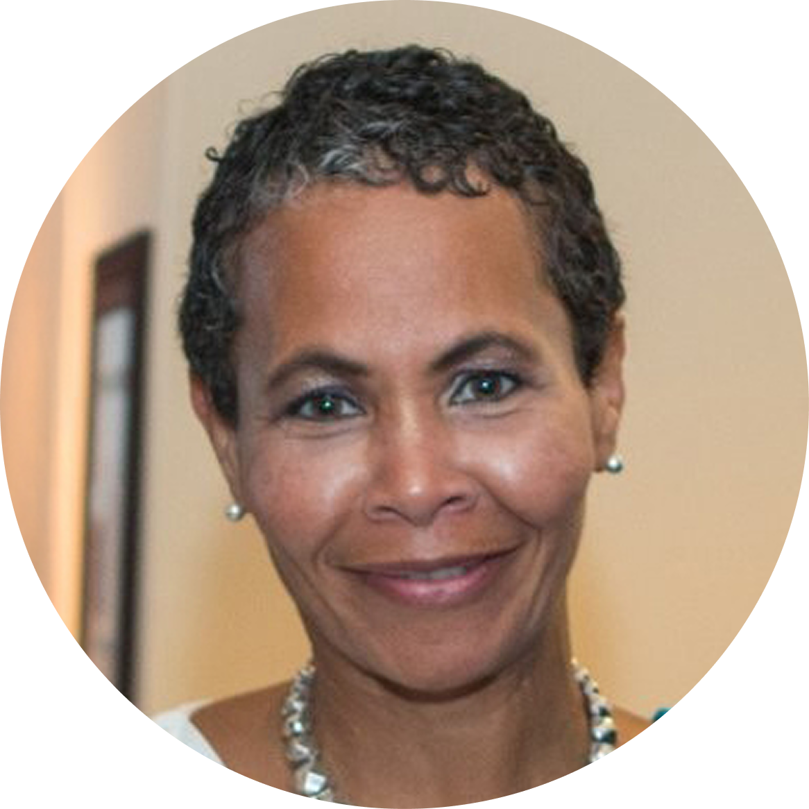 Close-up of our COO Leslie Wise, with short curly hair, wearing pearl earrings and a necklace.