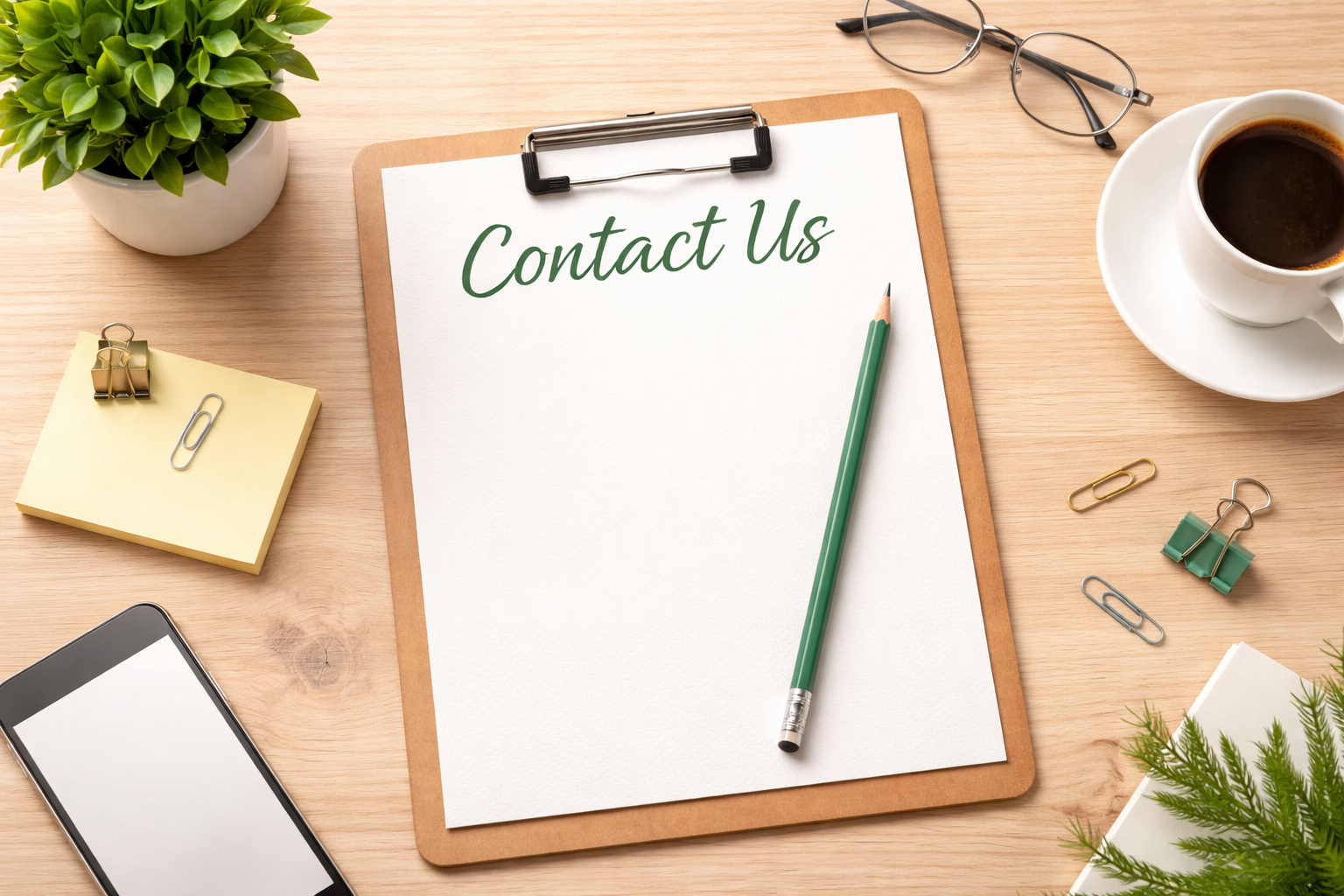 A desk with a clipboard that says 'Contact Us', a green pencil, a pair of glasses, a cup of coffee on a saucer, a smartphone, sticky notes with paper clips, a small plant in a white pot, and some scattered paper clips.