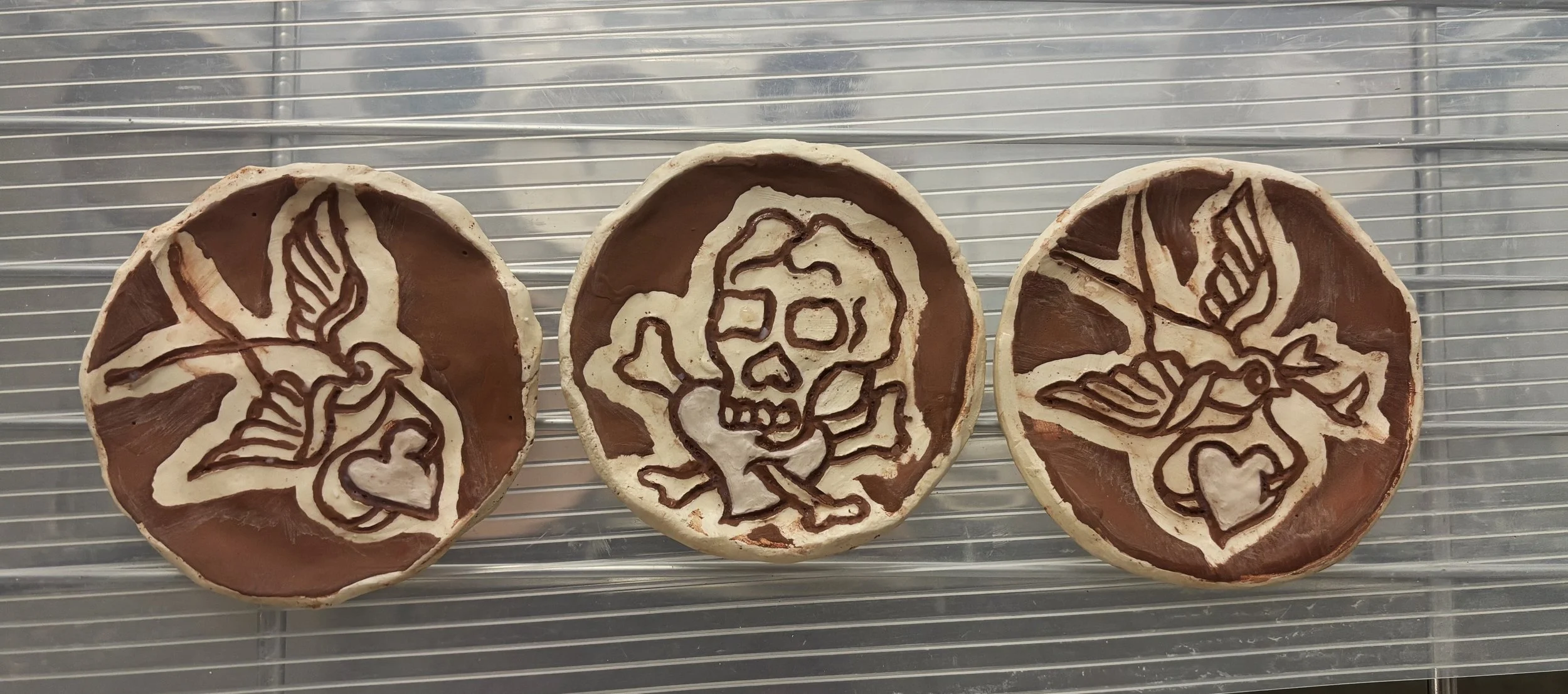 Valentine's saucers, 2 of 2. These are inspired by Sailor Jerry flash with the designs carved in. Ready for firing!