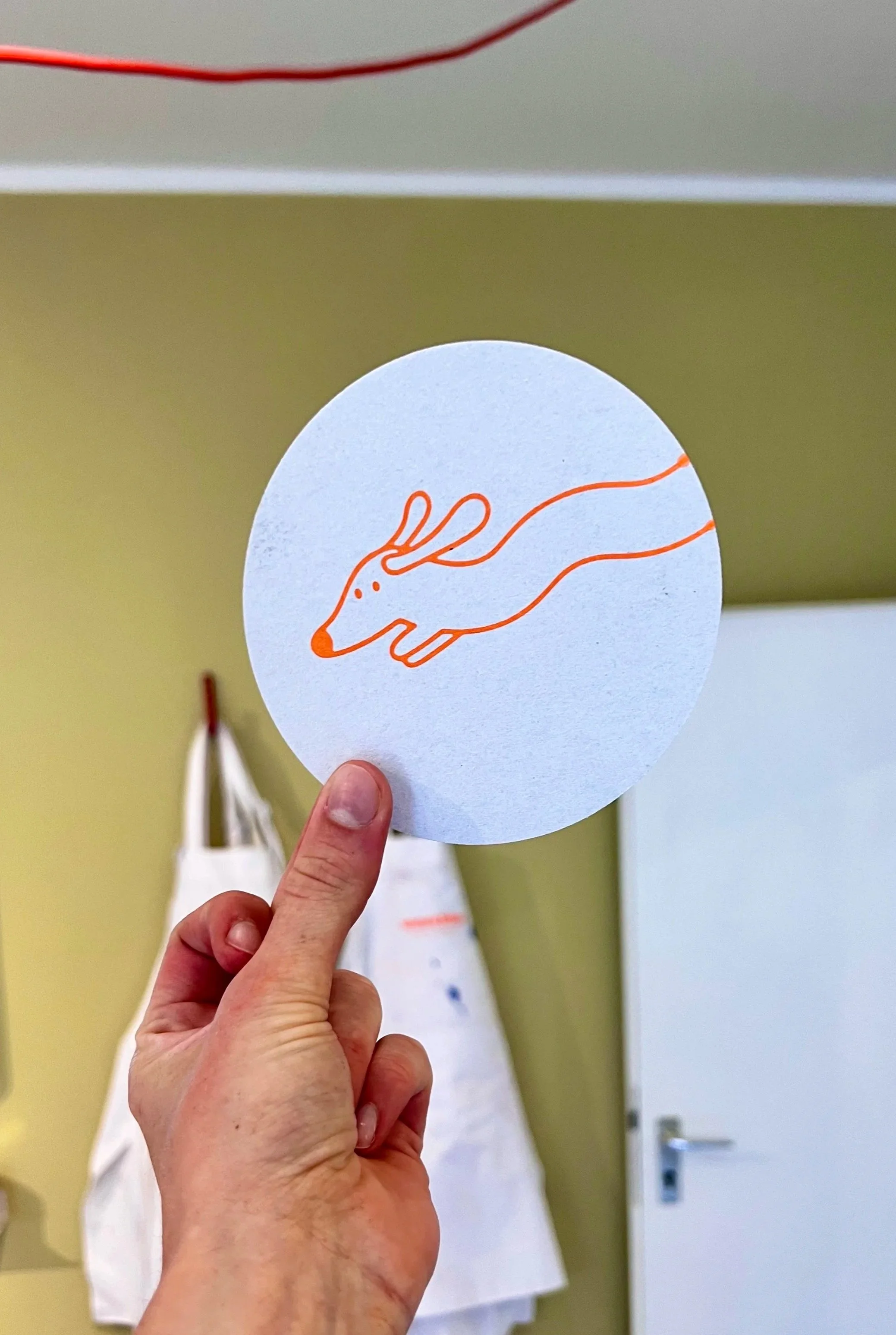 Illustration eines Dackels auf einem Bierdeckel in orange auf einem weißen Kreis, gedruckt im Atelier Wuschka.
