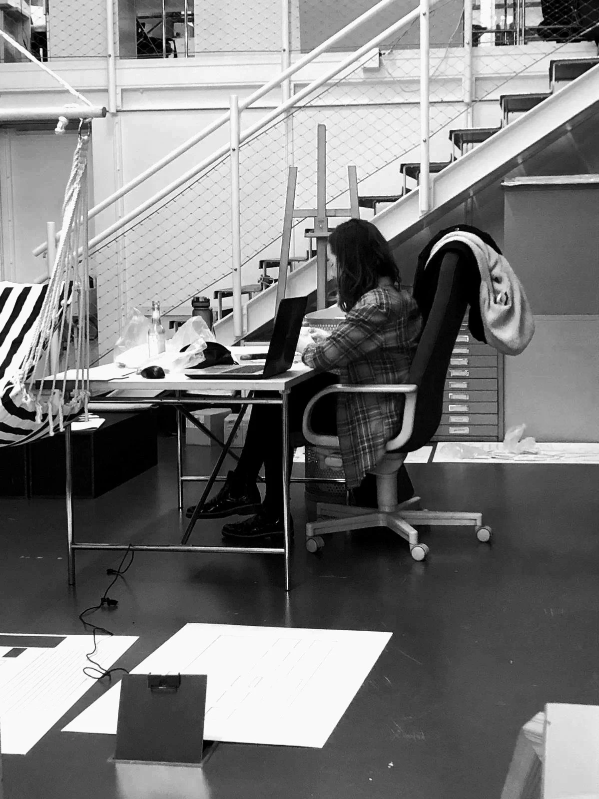 Frau arbeitet an einem Schreibtisch in einem Büro mit Laptop, Papiere und eine wiederverwendbare Wasserflasche.
