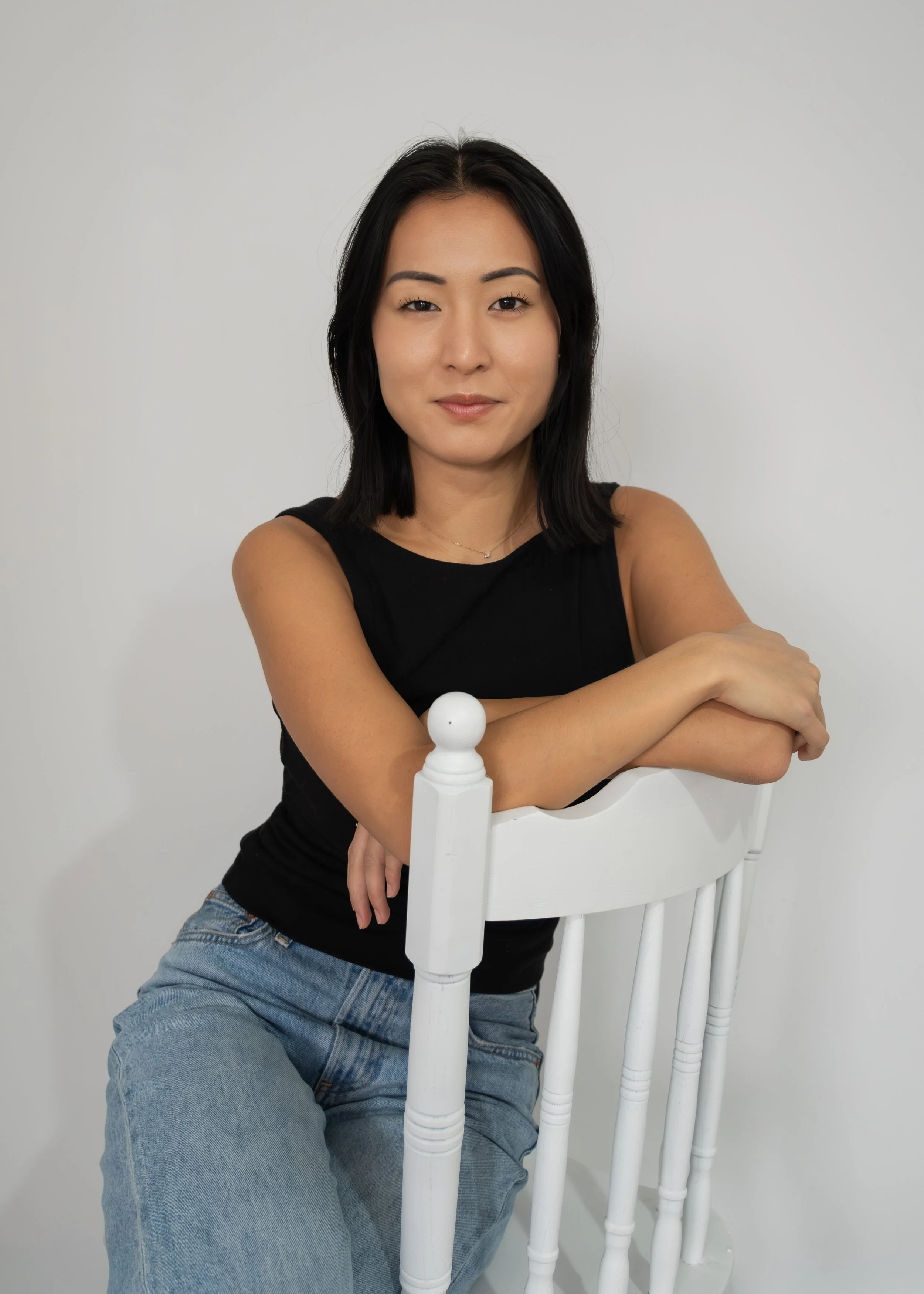 Portrait of Skye J Blount sitting on a chair against a light gray background.