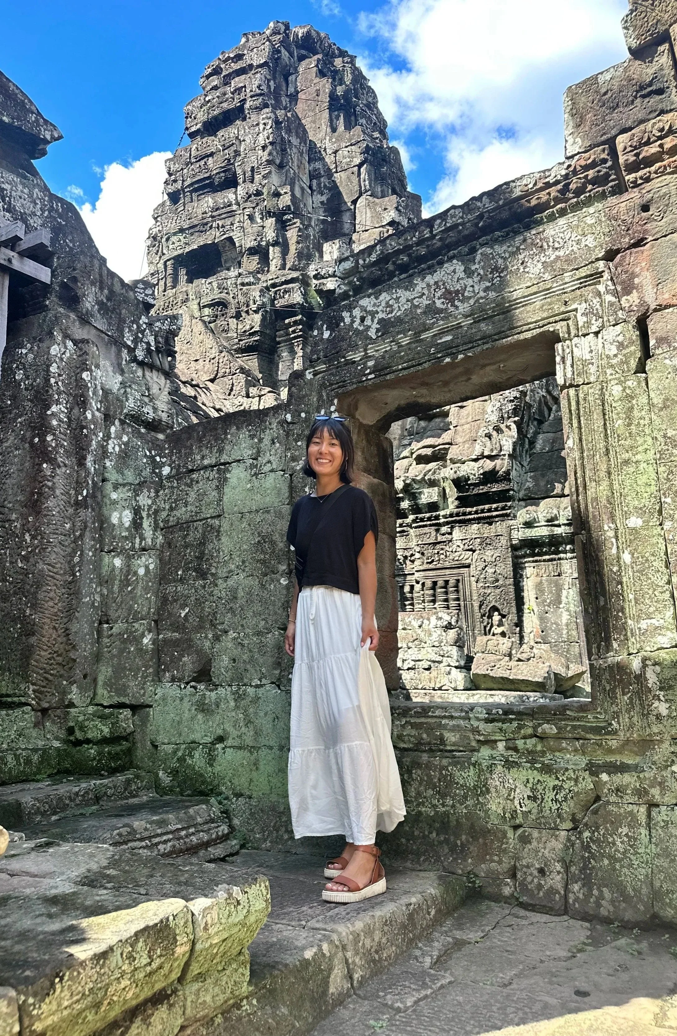 Skye J Blount standing in front of ancient Cambodian stone ruins.