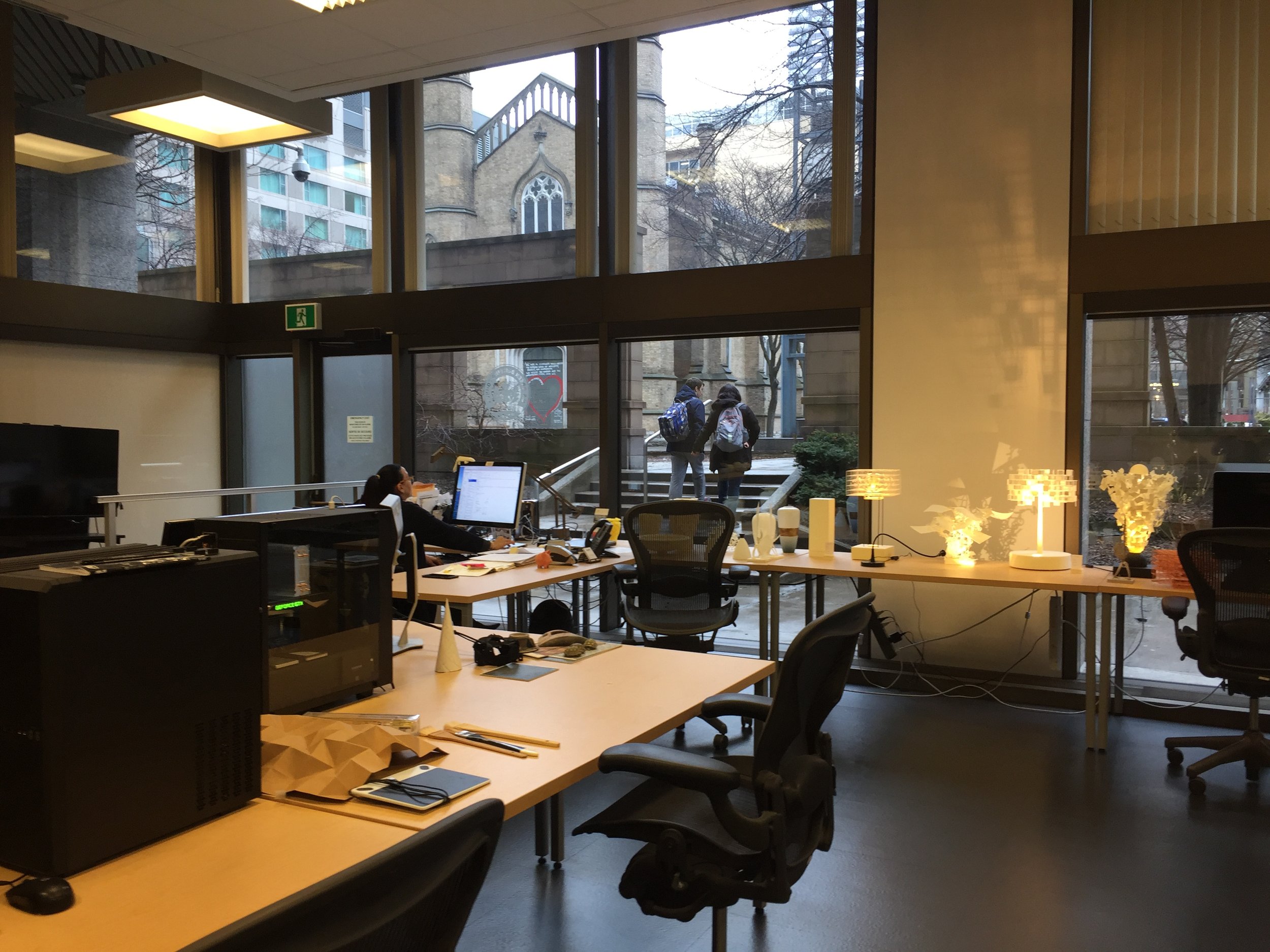 A 3D printing lab with large windows and 3D printed lamps on a desk near the windows.