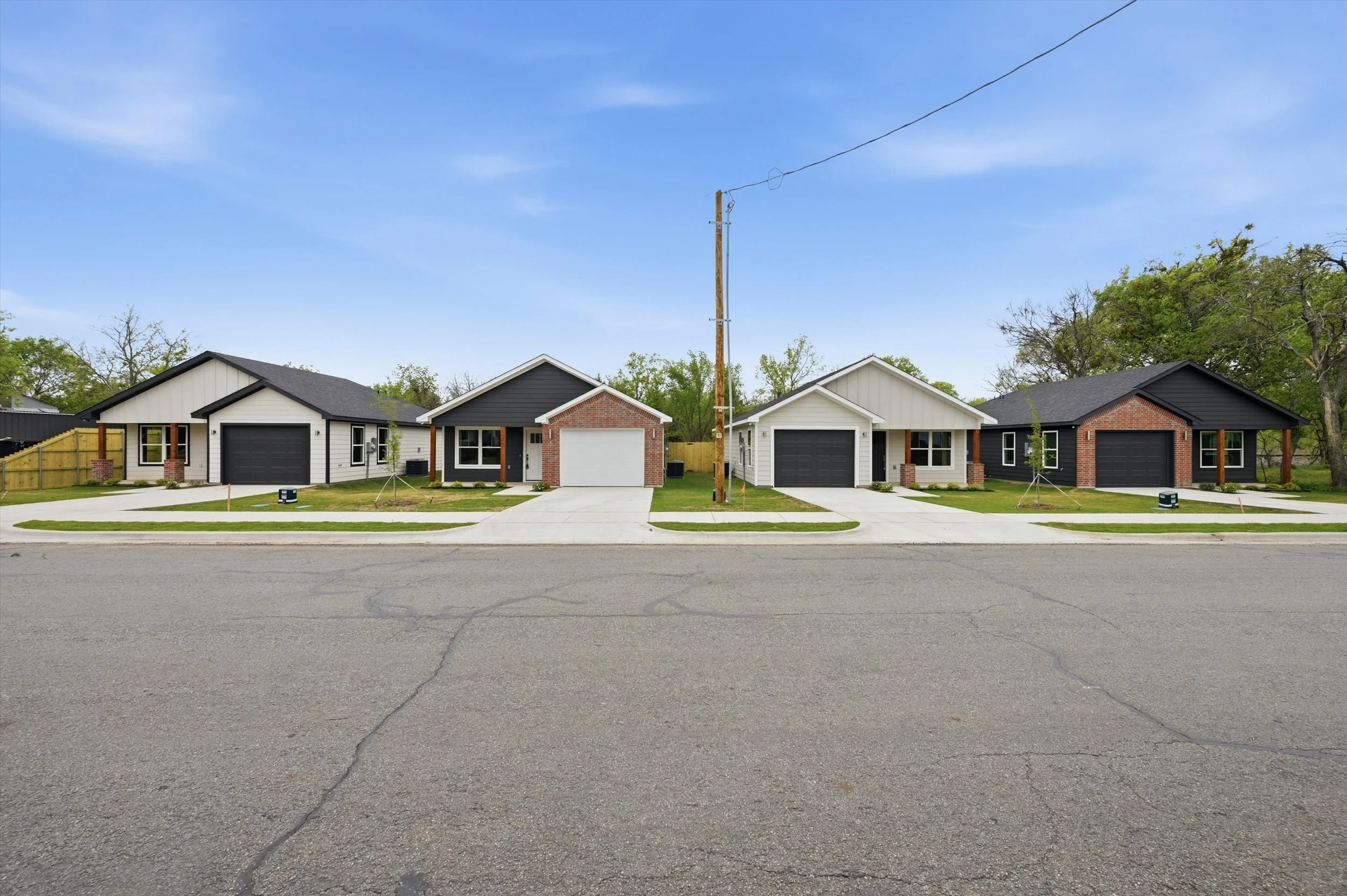 A brick building with a light gray roof, surrounded by green trees and grass, with a sidewalk in front. There is a sign on the left reading 'Ambiance Community.'