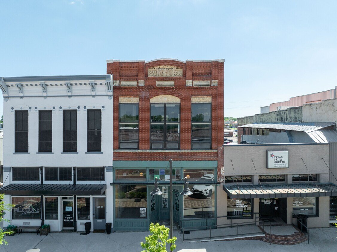 Photo of three adjacent storefronts on a city street with a clear sky above.