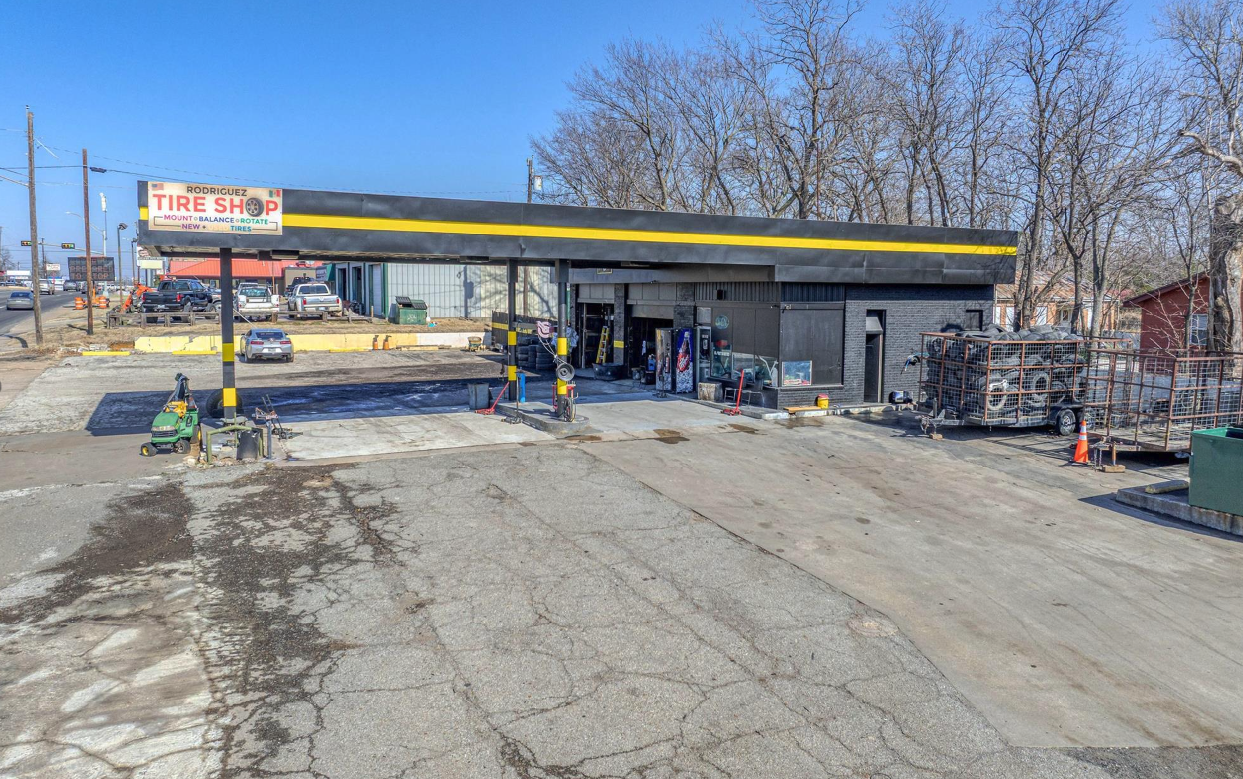 An aerial view of a shopping plaza with multiple storefronts including Family Dollar, Dollar General, and other stores, parking lots with a few cars, and surrounding residential houses in the background.