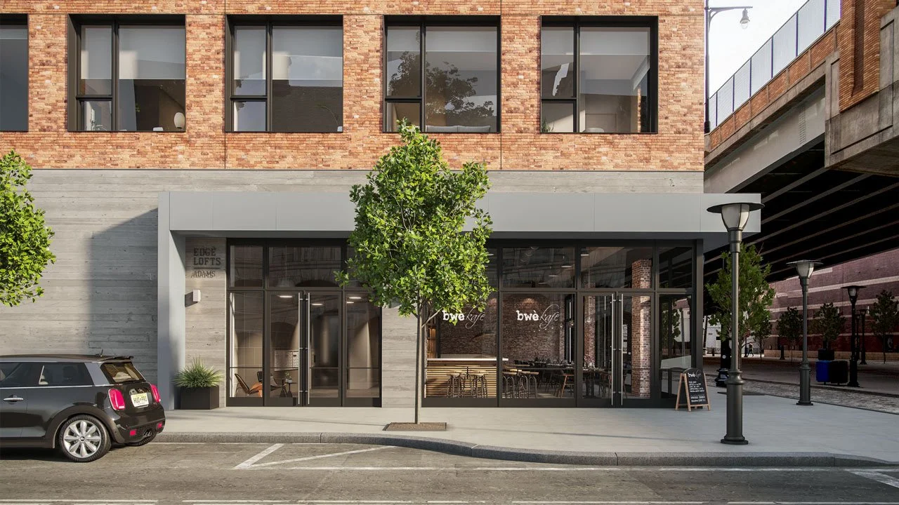 Street view of a modern building with a cafe named 'bwe cafe' in the ground floor, trees, parked car, and street lamps.