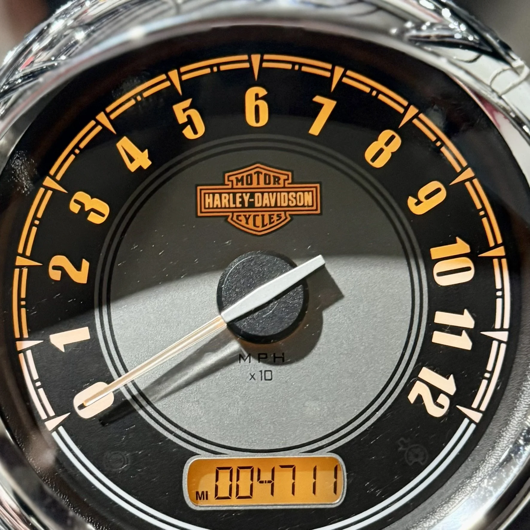 Close-up of a Harley-Davidson motorcycle speedometer showing approximately 7 miles per hour, with an odometer reading 84,711 miles.