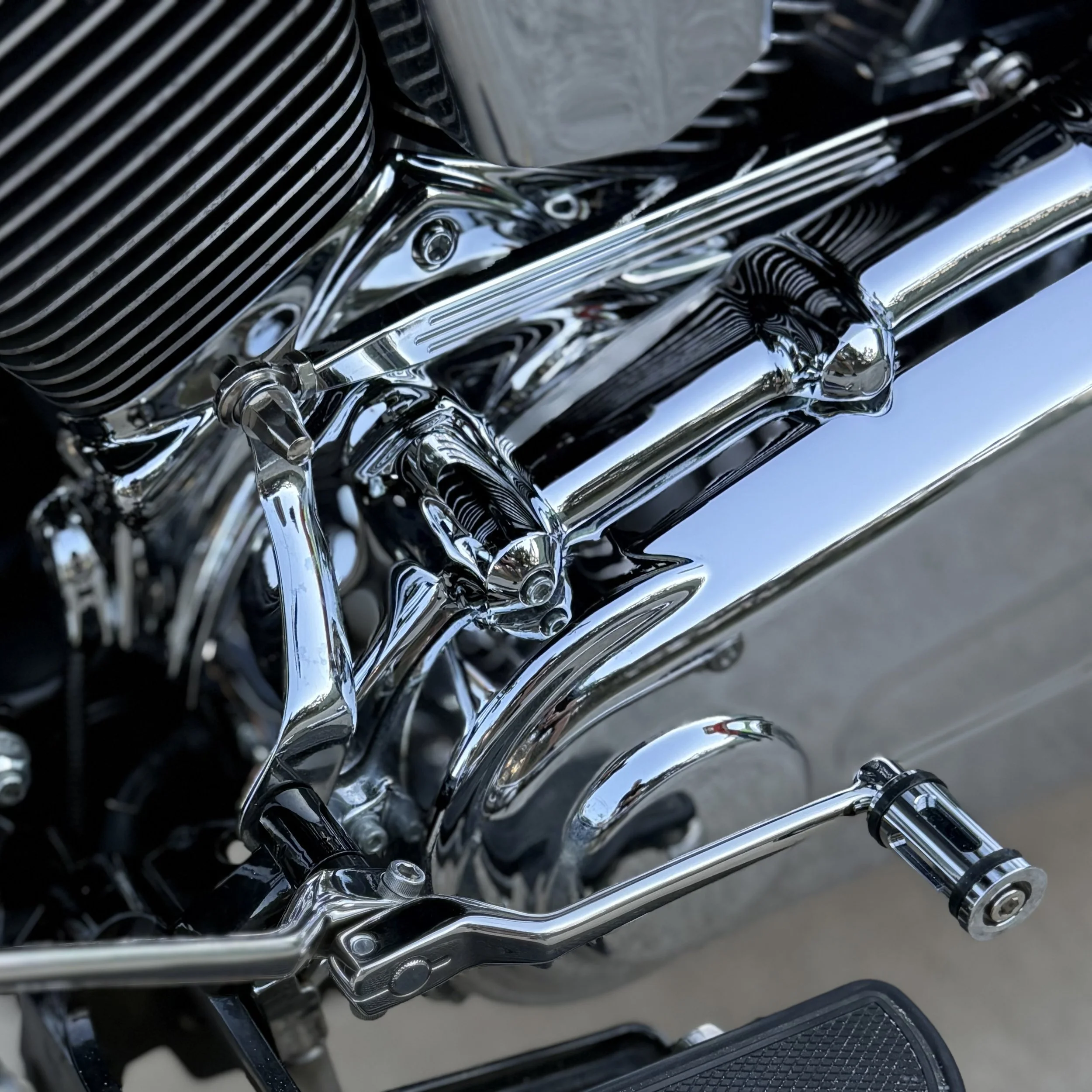 Close-up of a shiny chrome motorcycle engine and foot pedal.