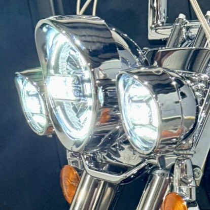Close-up of a motorcycle headlight with chrome details and orange turn signals.