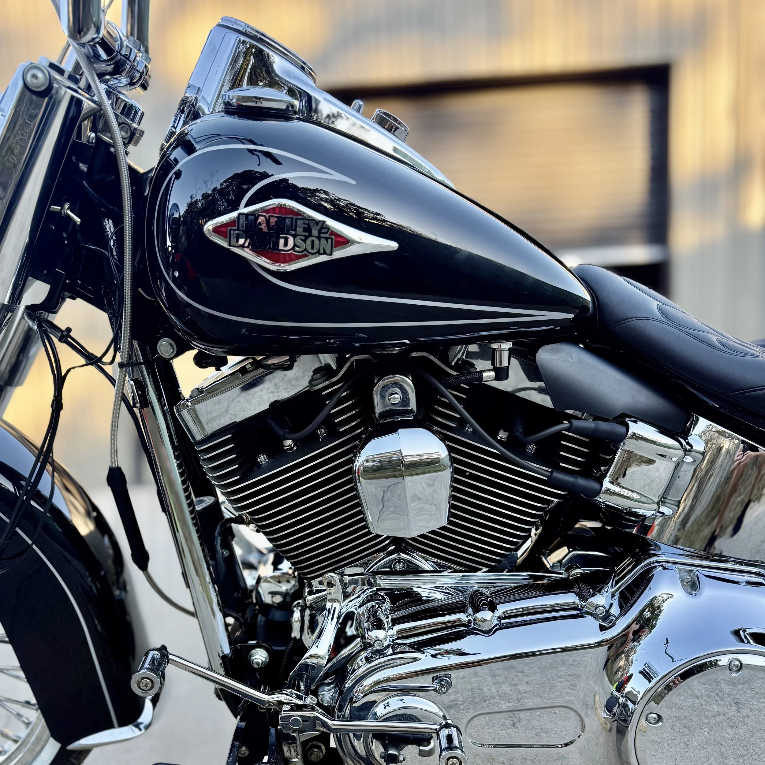 Close-up of a black Harley Davidson motorcycle with chrome details and logo on the fuel tank, parked outside.