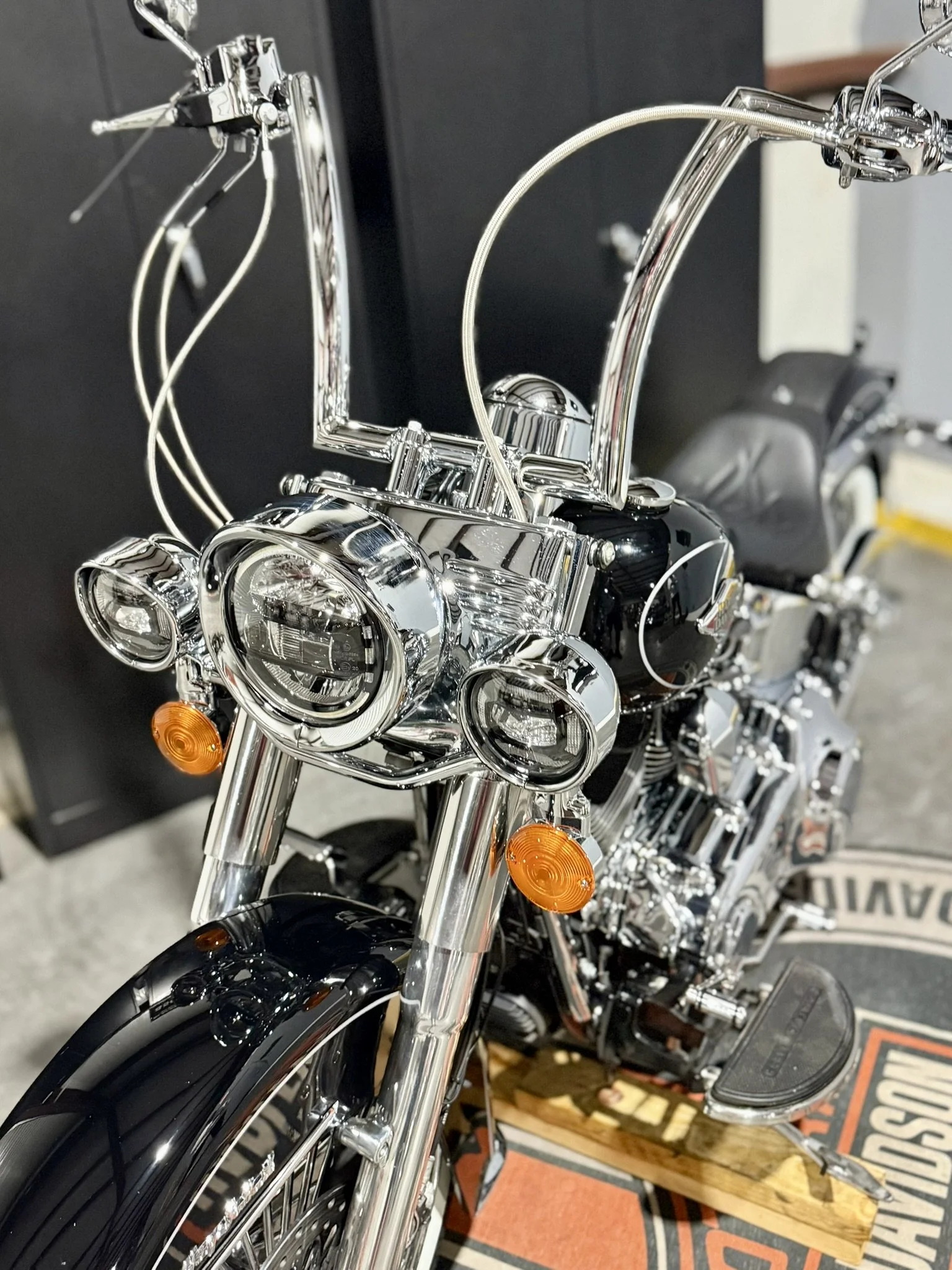 Close-up of a shiny black and chrome motorcycle with dual front headlights, orange turn signals, and detailed handlebars.